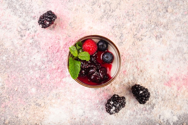 Греческий йогурт с ягодным джемом и мятой в керамической чашке фото высокого качества