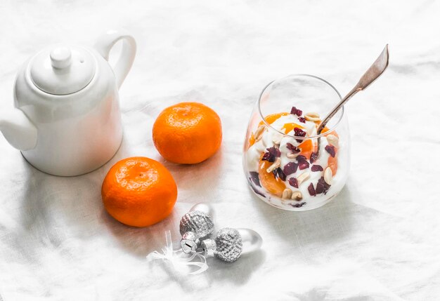 Greek yogurt with tangerine dried cranberries and nuts on a light background top view