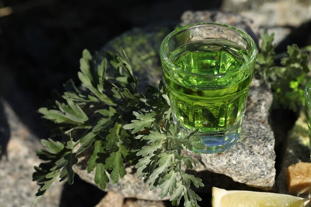 green absinthe drink on the black background with sugar and lime. Stones background