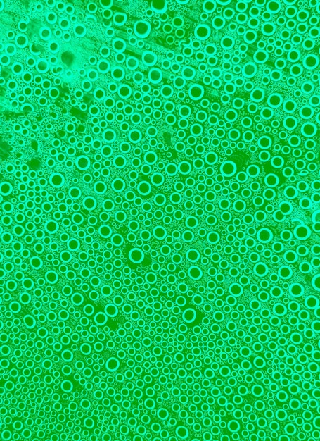 투명한 플라스틱 표면에 있는 녹색 추상 방울 물 거품의 일반 원 추상 배경 모양의 부드러운 작은 거품