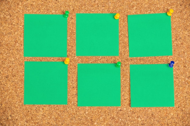 Photo green adhesive notes sticked with pins on notice board