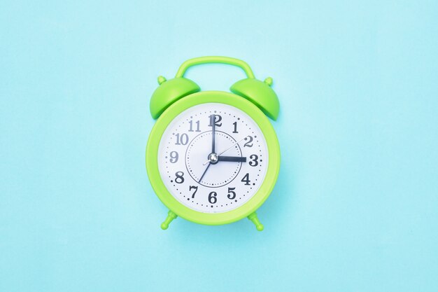 Photo green alarm clock on a blue background