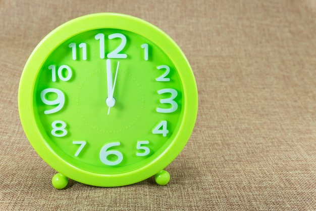 갈색 자루 배경에 녹색 알람 시계는 오전 1200시에 표시됩니다.