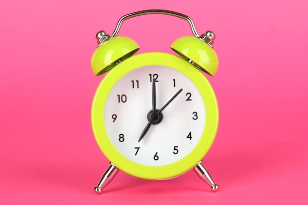 Green alarm clock on pink background