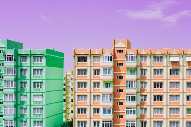 Фото Зеленые и оранжевые панельные архитектурные дома на фоне фиолетового неба девятиэтажные старые городские жилые дома с окнами