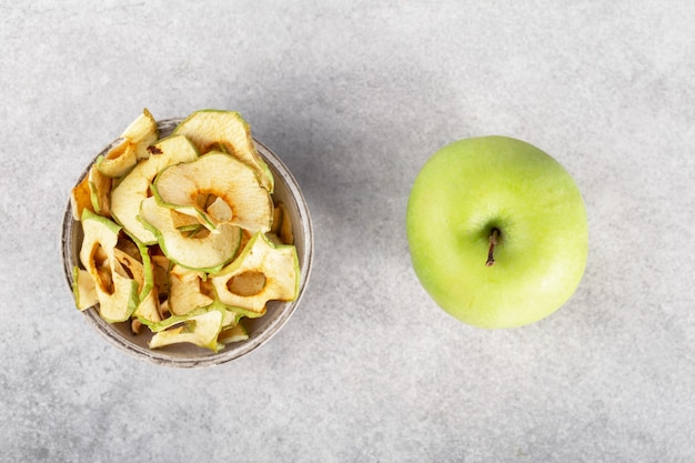 зеленые яблочные чипсы в серой миске на сером фоне