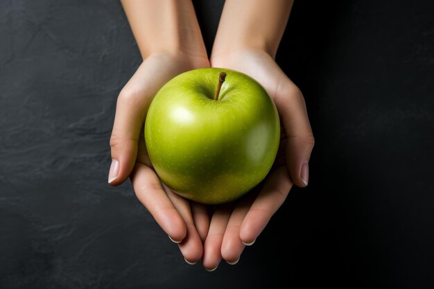 Зелёное яблоко в женской руке на сером фоне Диета по снижению веса