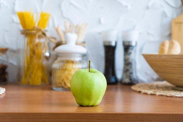 Green apple on the kitchen table closeup