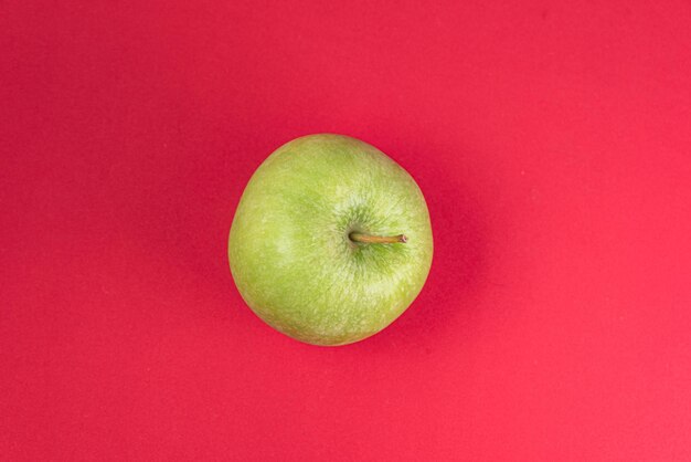 Green apple on the red background