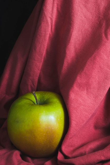 A green apple on a red cloth background