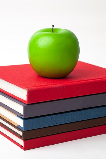 a green apple on stack of new books