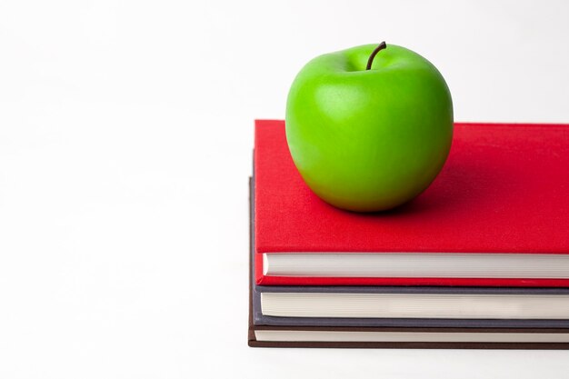 Photo a green apple on stack of new books