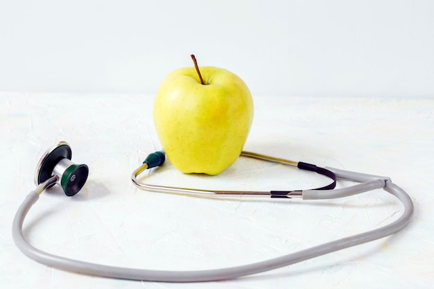 Green apple and stethoscope on a light background