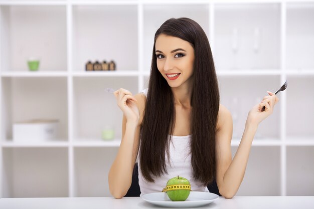 green apple on a white plate, fork, knife, weight loss, healthy diet, yellow measuring tape, weight loss