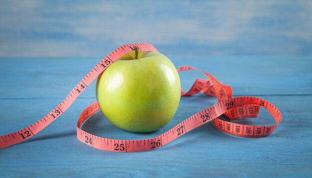 Green apple with measuring tape on the blue background