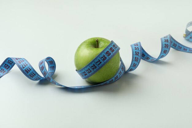 Green apple with measuring tape on white