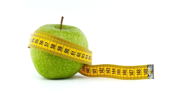green apple wrapped with a yellow tape measure on white background