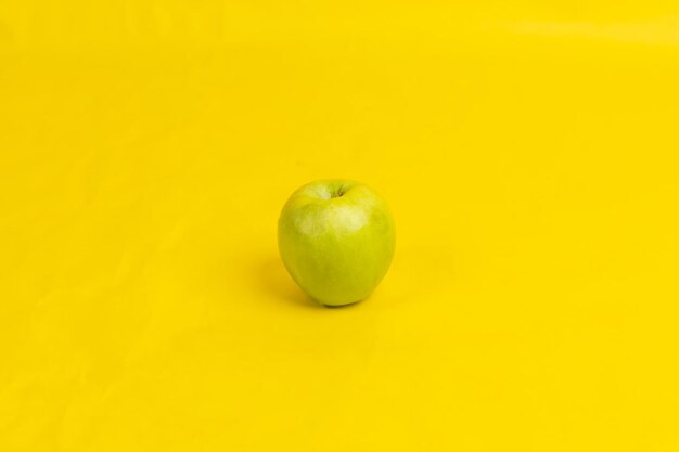 A green apple on a yellow background