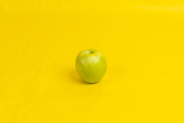 a green apple on a yellow background