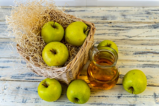 Green apples basket with apples and jug with apple juice on wooden background