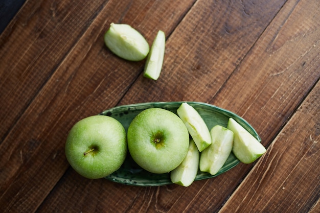 Green apples on wooden table. Close up. Concept of healthy food. Sliced green apple on cutting board