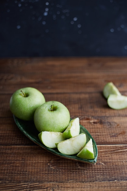 Green apples on wooden table. Close up. Concept of healthy food. Sliced green apple on cutting board