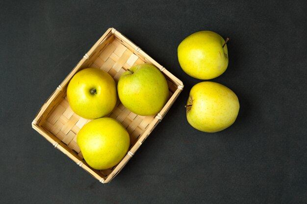 Green appples in basket on dark wooden surface