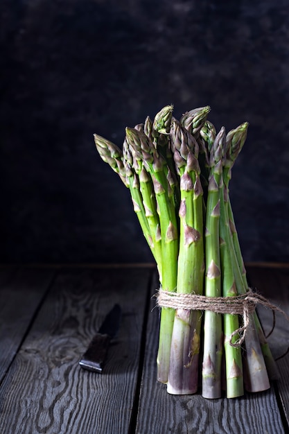 Asparagi verdi su uno sfondo di legno scuro. concetto di cibo crudo.