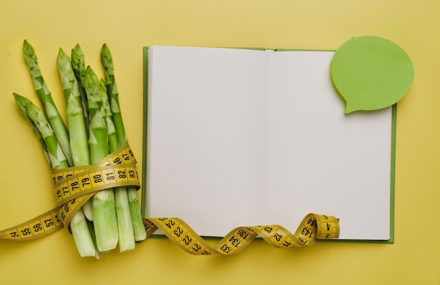 Photo green asparagus and measuring tape isolated on yellow