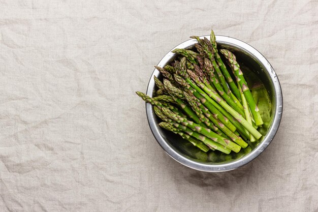 Photo green asparagus in a metal bowl on a linen tablecloth