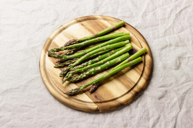 Photo green asparagus on a round wooden cutting board