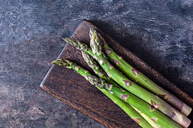 Green asparagus on a wooden cutting board on a dark background Raw food concept