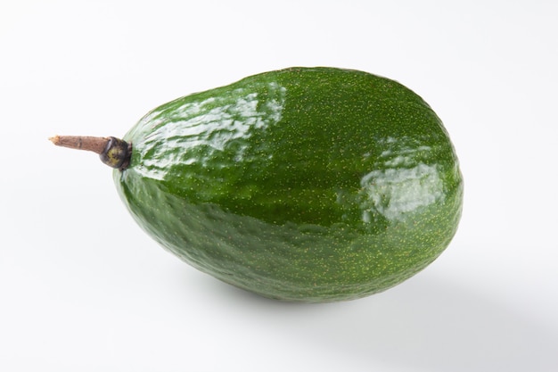 Green avocado fruit isolated on white surface.