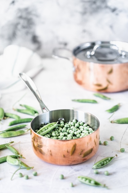 Green baby peas in pan on white