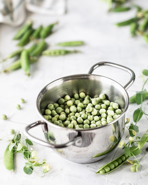 Green baby peas in pan on white