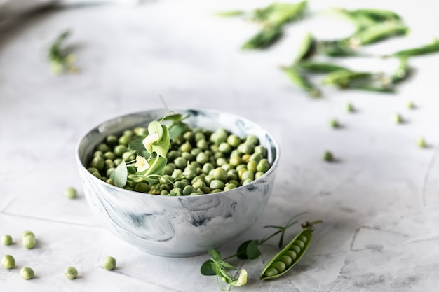 Green baby peas in pan on white