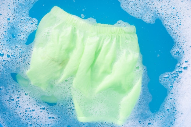 緑のベビーショーツは、ベビーランドリー洗剤水溶解、洗濯布、ランドリーコンセプトに浸します。