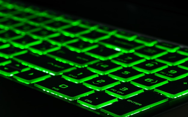 Green backlight backlit on gaming laptops computer in the dark Close up