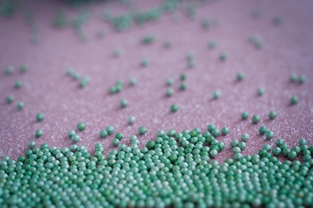 Фото Зеленые шариковые кристаллические цукровые точки на блестящем розовом фоновом украшении для кондитерских изделий