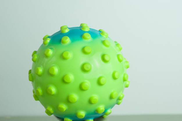 A green ball with green dots sits on a table.