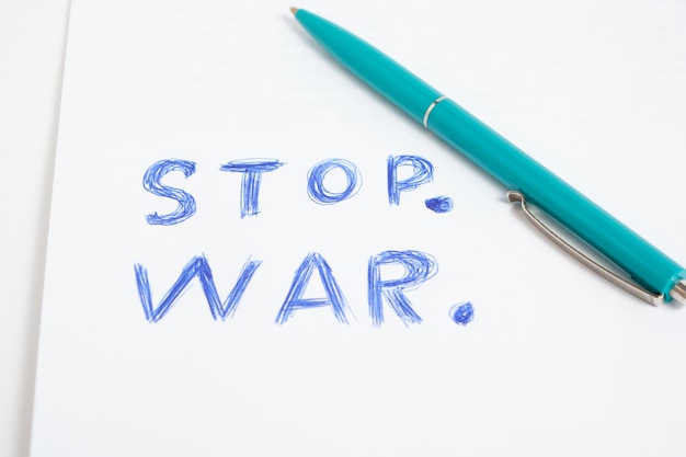Green ballpoint pen and inscription stop war white sheet