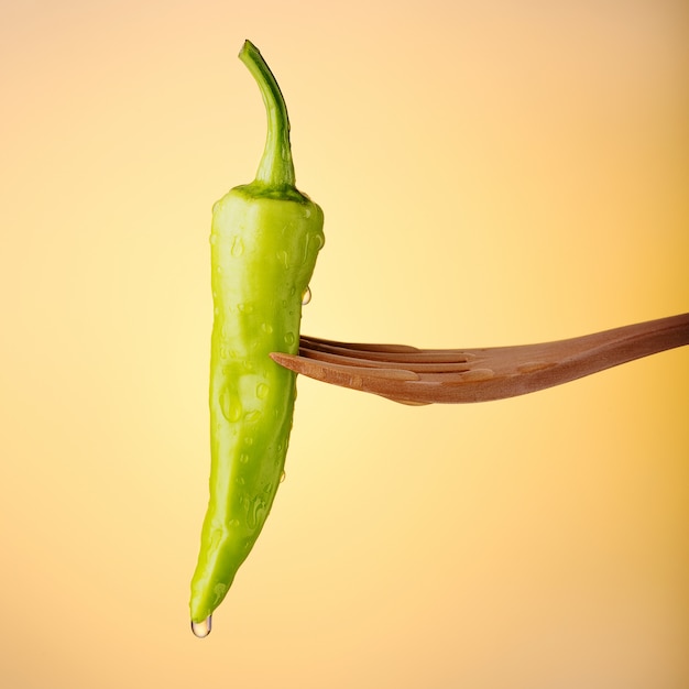 Green banana pepper on orange background