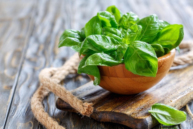 Green basil leaves in a wooden bowl