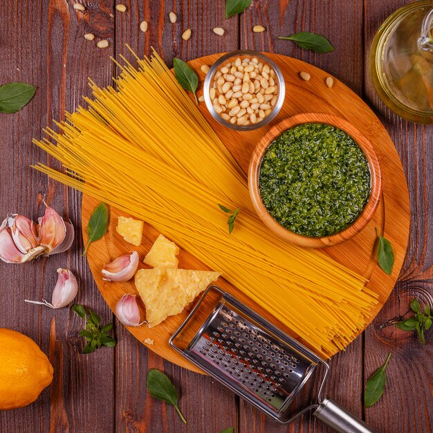Green basil pesto - italian recipe ingredients on wooden table