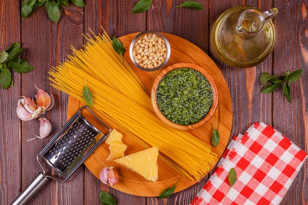 Green basil pesto - italian recipe ingredients on wooden table.