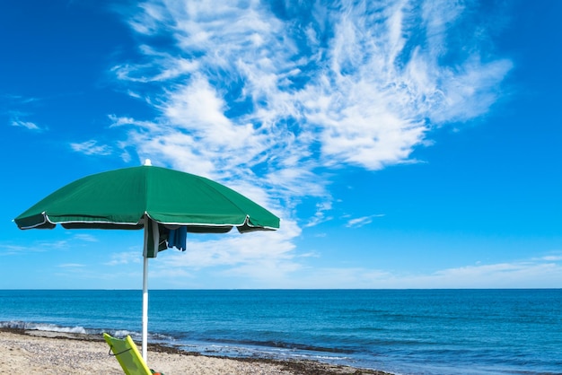 夏の曇りの日の海沿いの緑のビーチパラソル