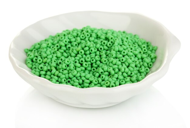 Perline verdi in piatto bianco isolato su bianco