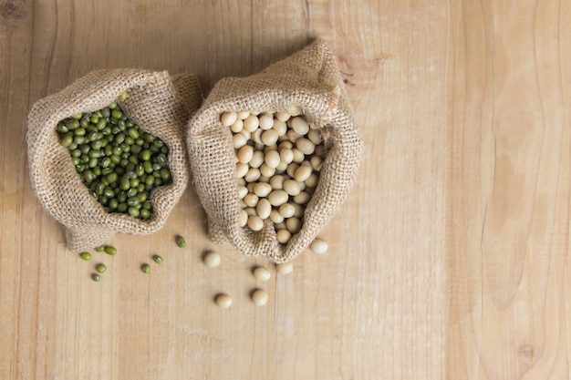 Green bean and soy bean in sack on wooden table