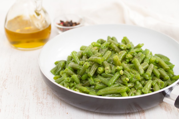 Green beans on frying pan on wooden surface