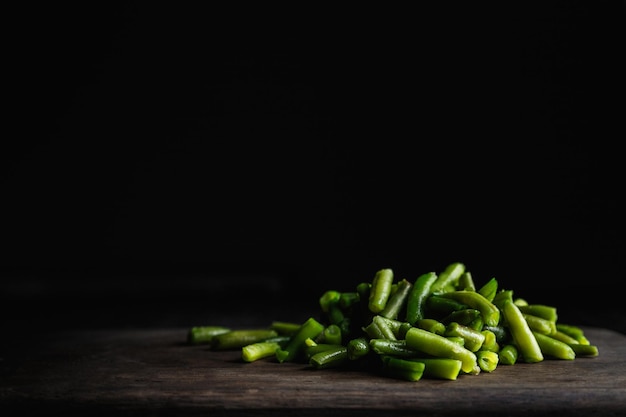 Green beans on wooden cutting board low key photo with copy space